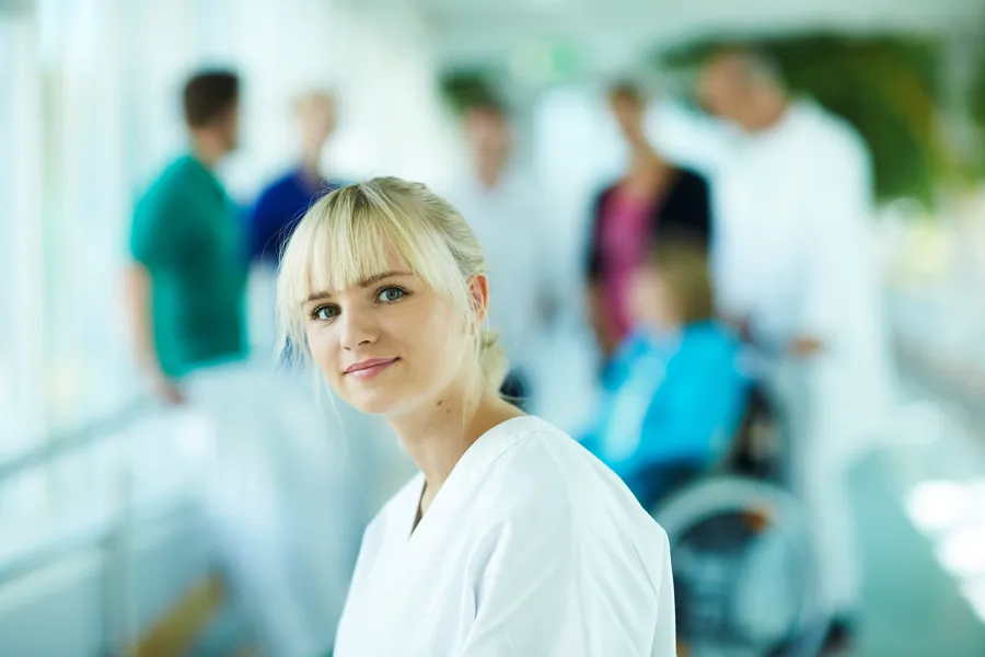 Jente kledd i hvitt står i fokus med en gjeng ulike klinikere i bakgrunnen