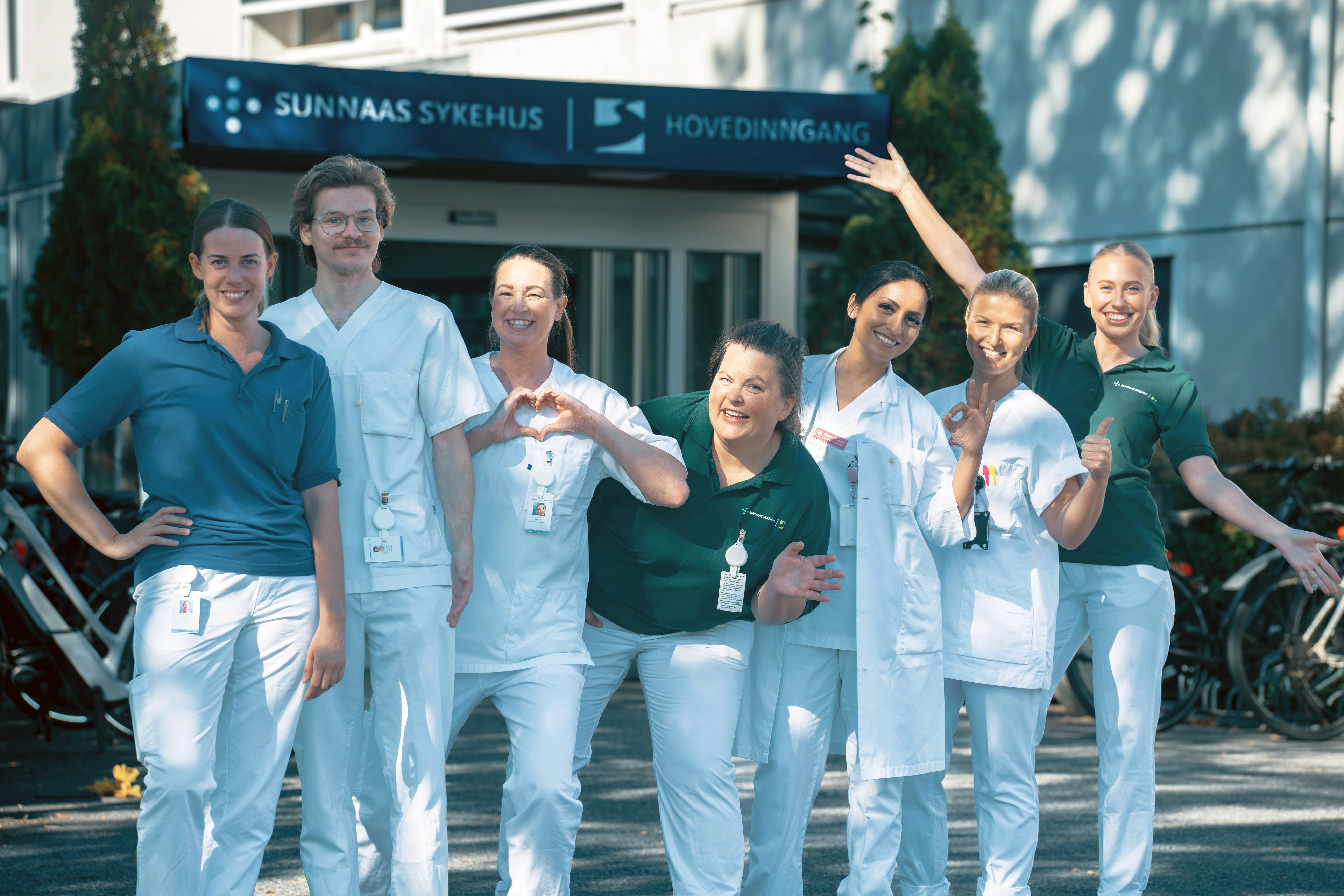 Syv helsepersonell står utenfor hovedinngangen til Sunnaas sykehus og ønsker velkommen