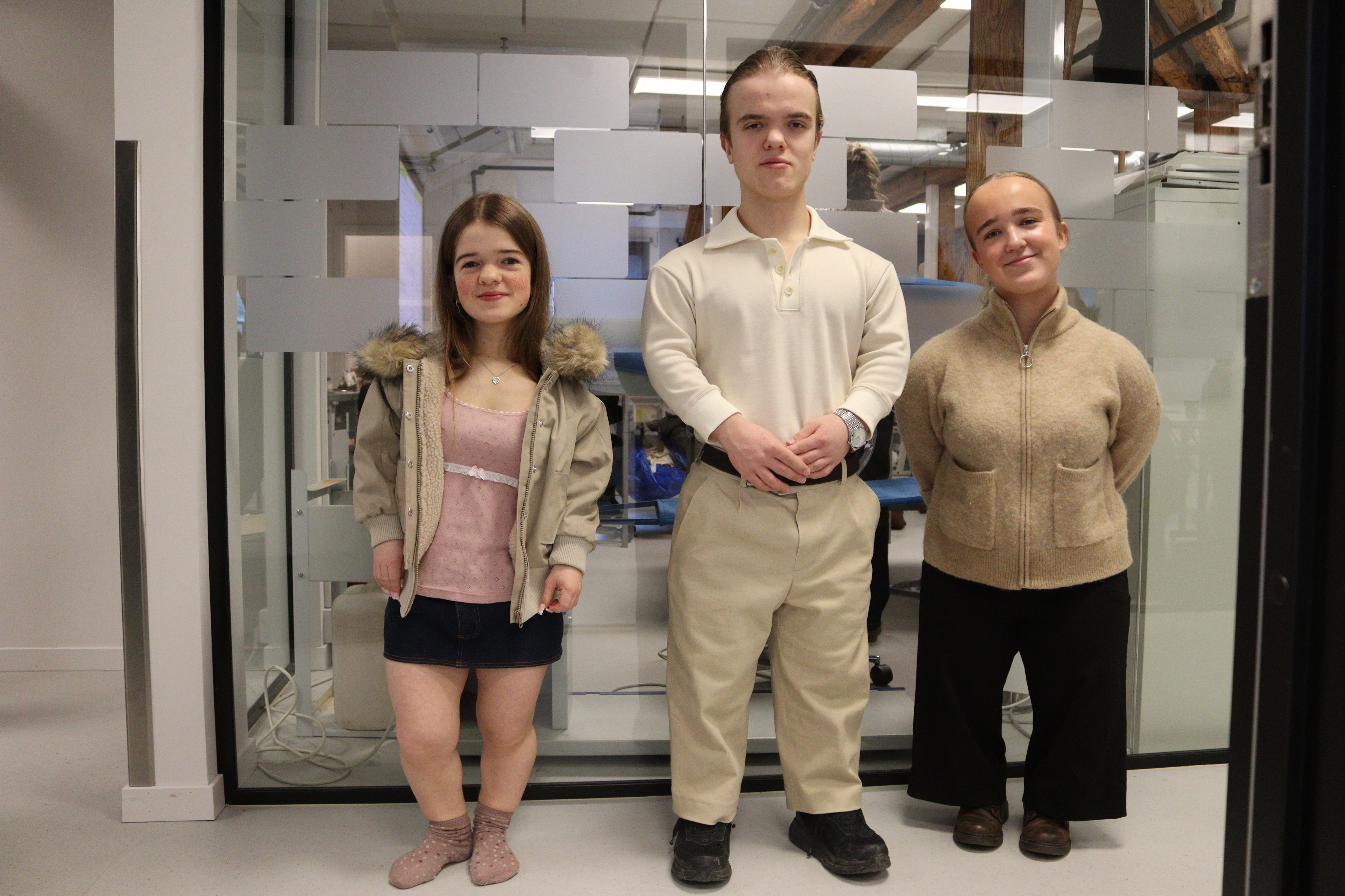 Tre kortvokste står ved glassvekk