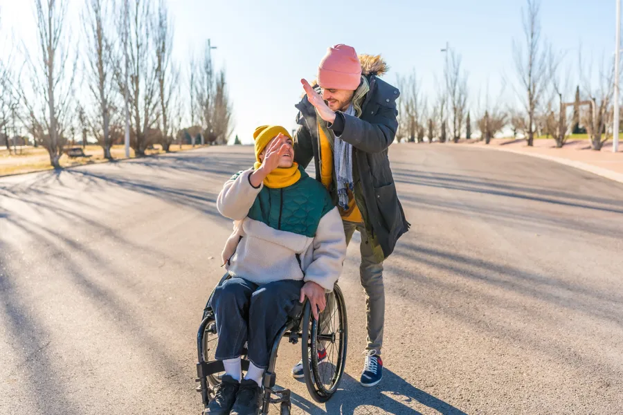 To personer, en med rullestol og en gående ute på tur