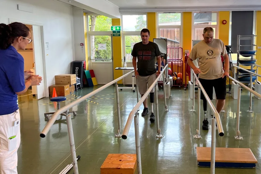 To Ukrainske soldater trener i gangbaner sammen med en fysioterapeut