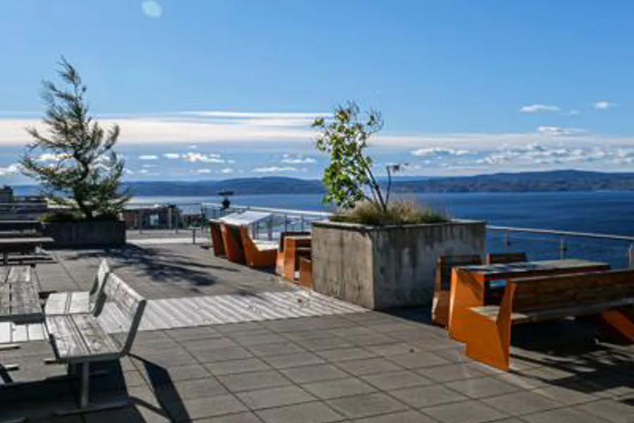 En uteplass med stoler og bord med utsikt over en vannmasse