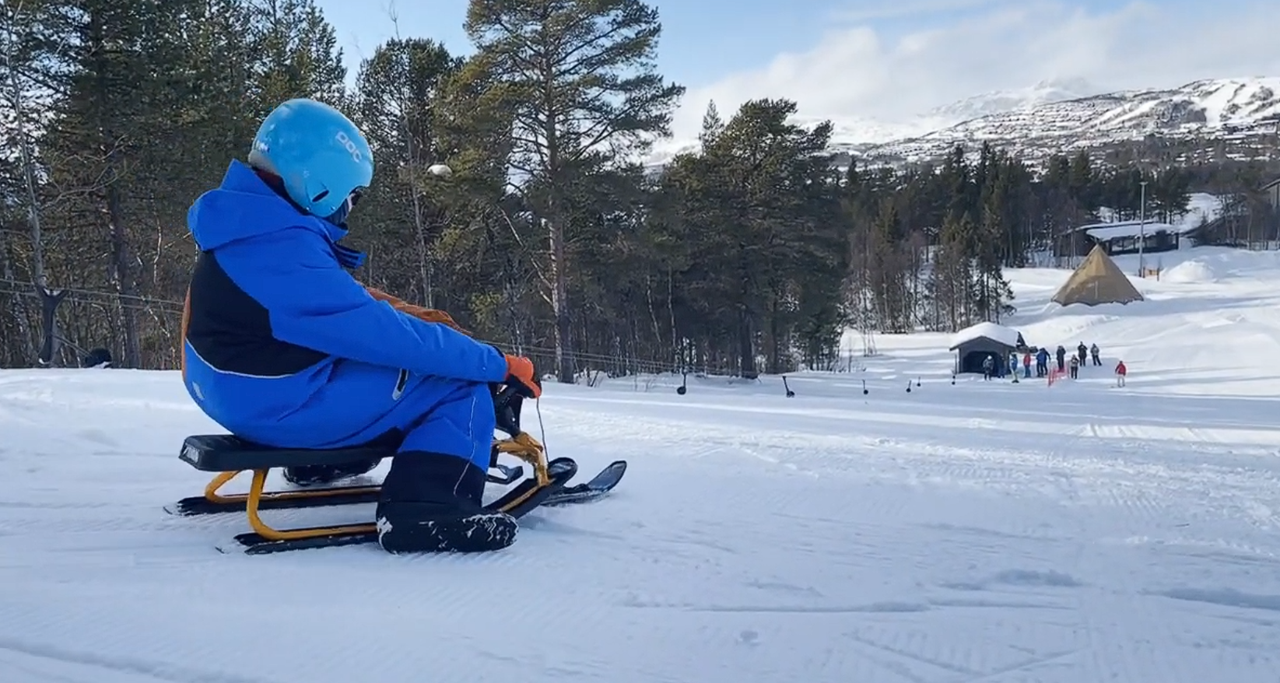 En person på en kjelke på et snødekt fjell