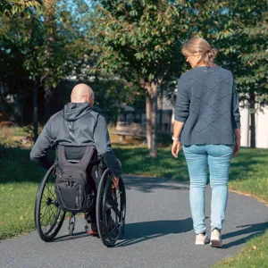 En mann i rullestol og en kvinne som på tur i en park