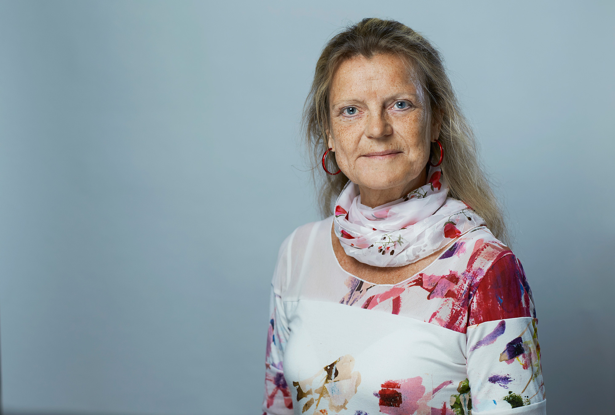 En mann med hvit skjorte og røde øredobber