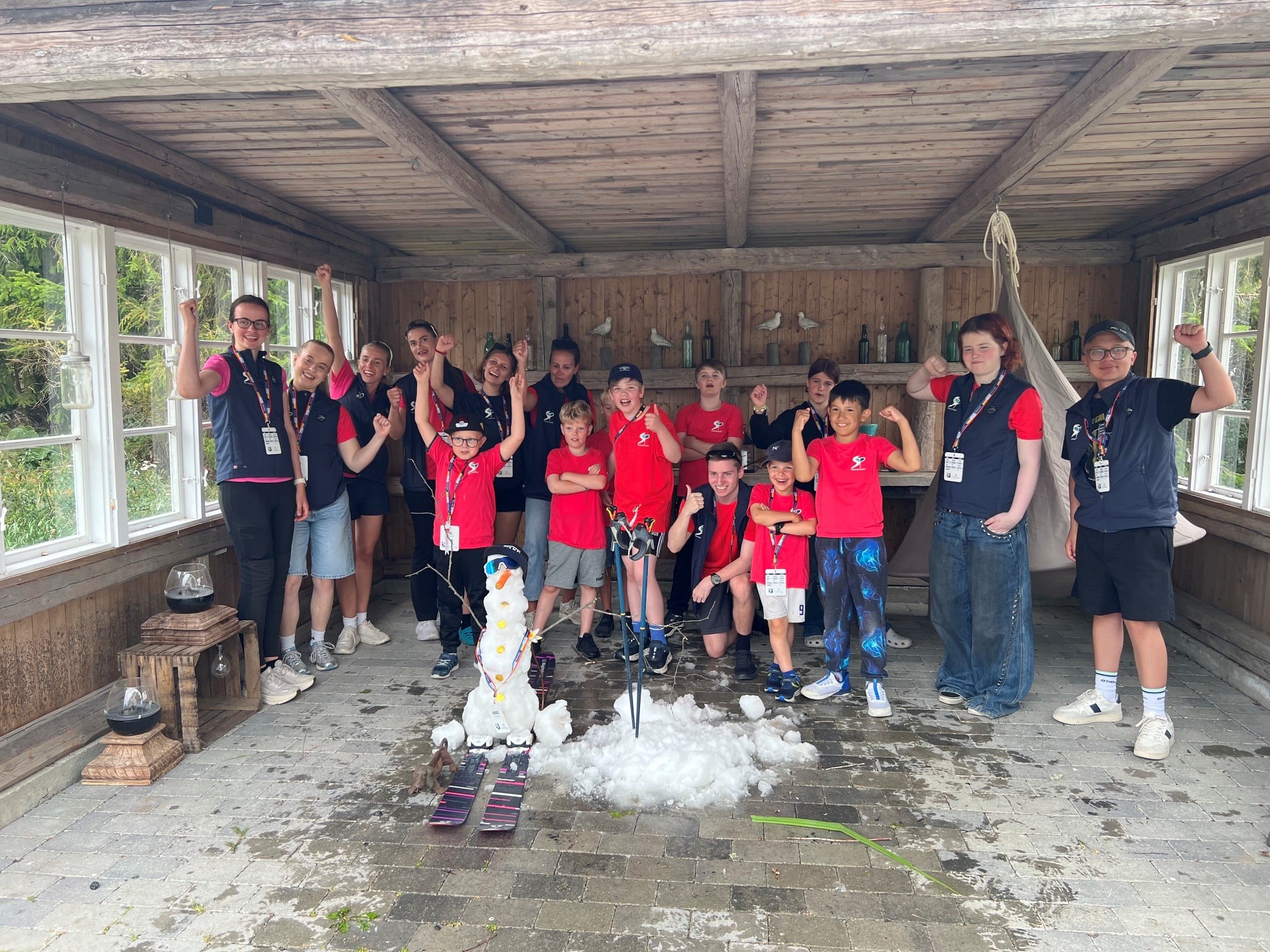 En gruppe med barn som poserer foran en snømann de har laget