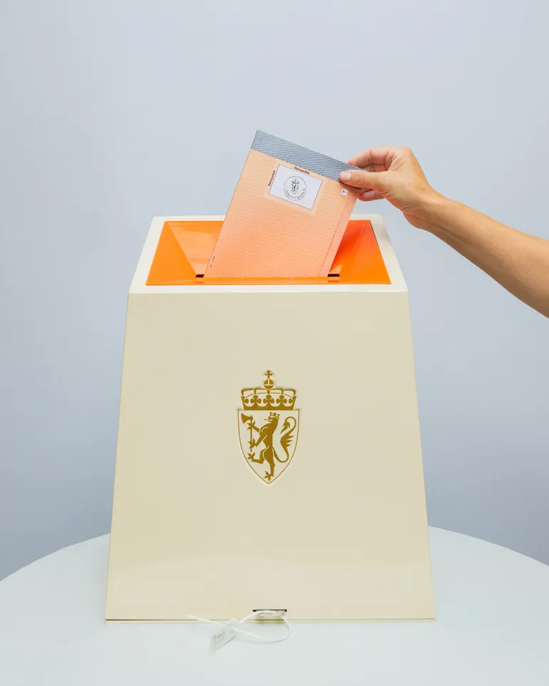 En hånd som legger en stemme i en valgurne.