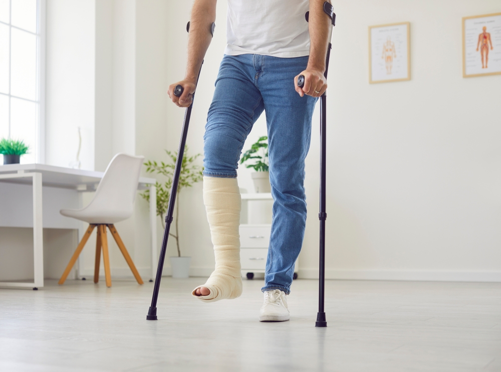 Mann som har gips på benet og går med krykker
