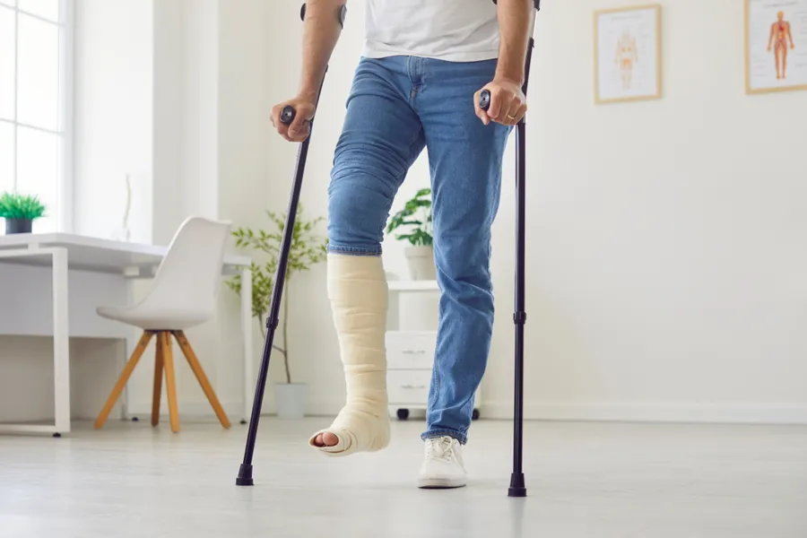 Mann som har gips på benet og går med krykker