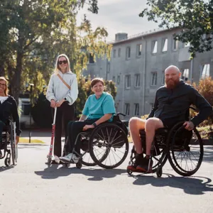 En gruppe mennesker som sitter i rullestol, en person står med krykker.
