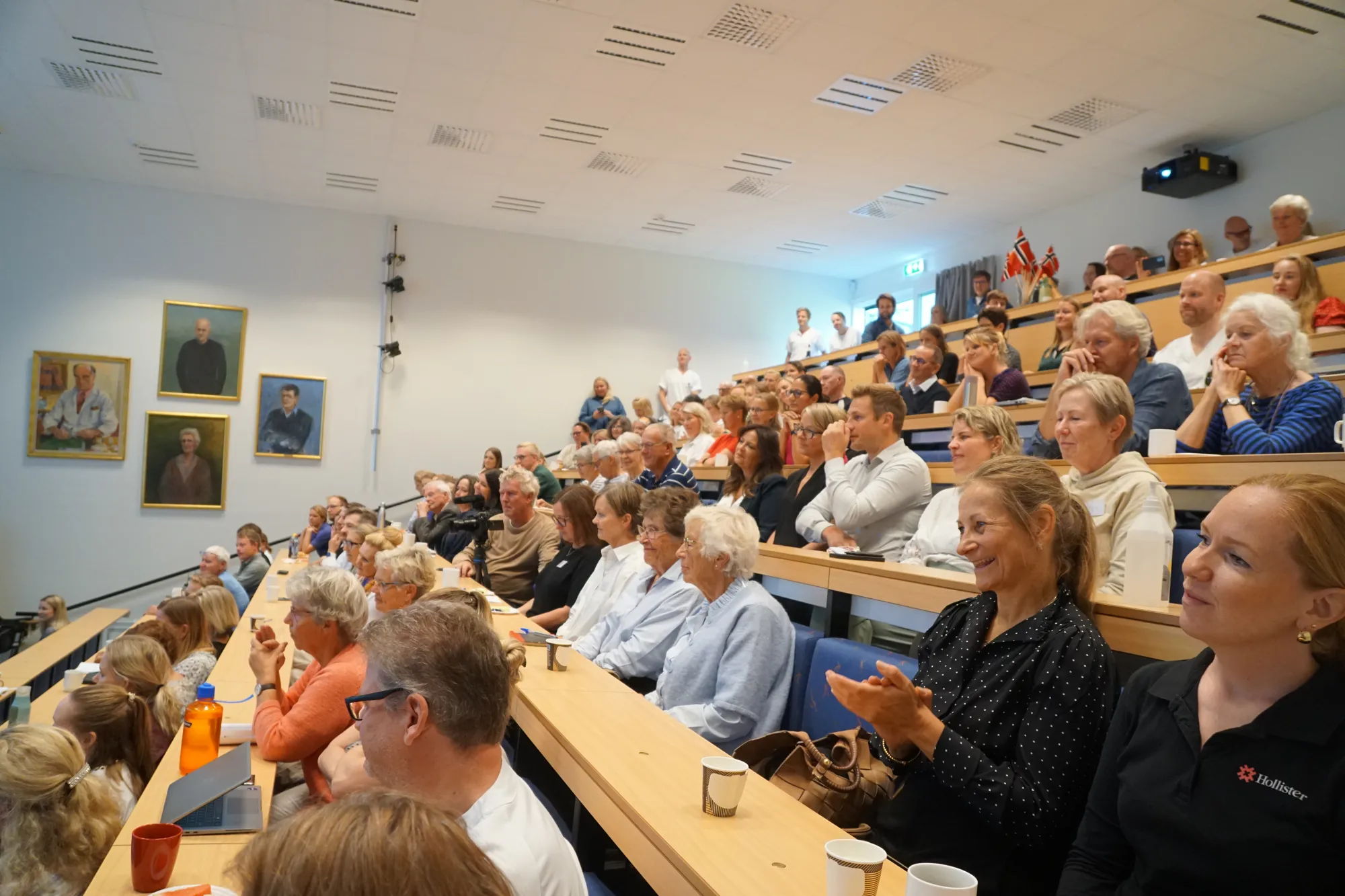 Et fullt auditorium med smilende mennesker som klapper
