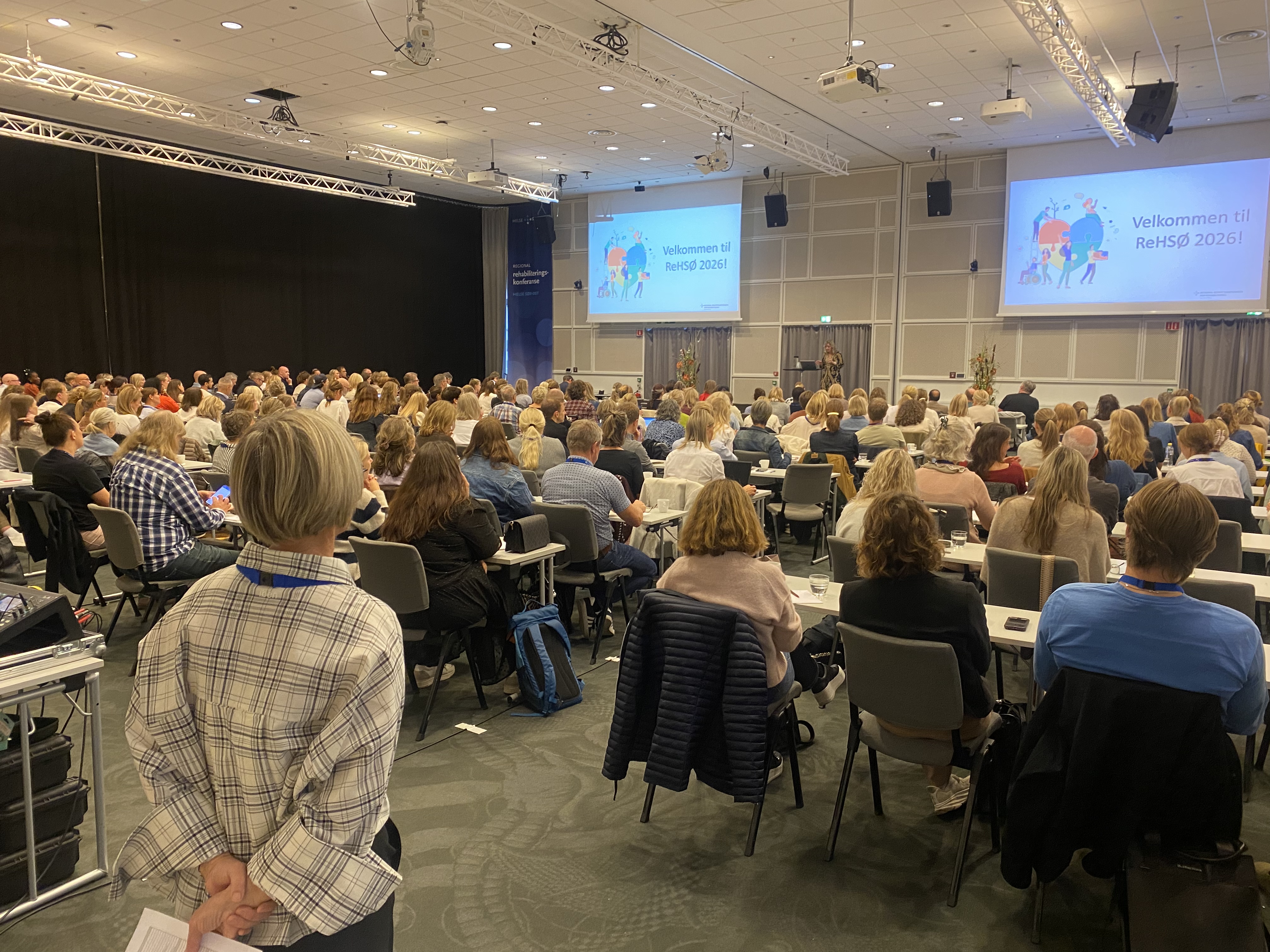 En gruppe mennesker som sitter i et rom og ser på en skjerm