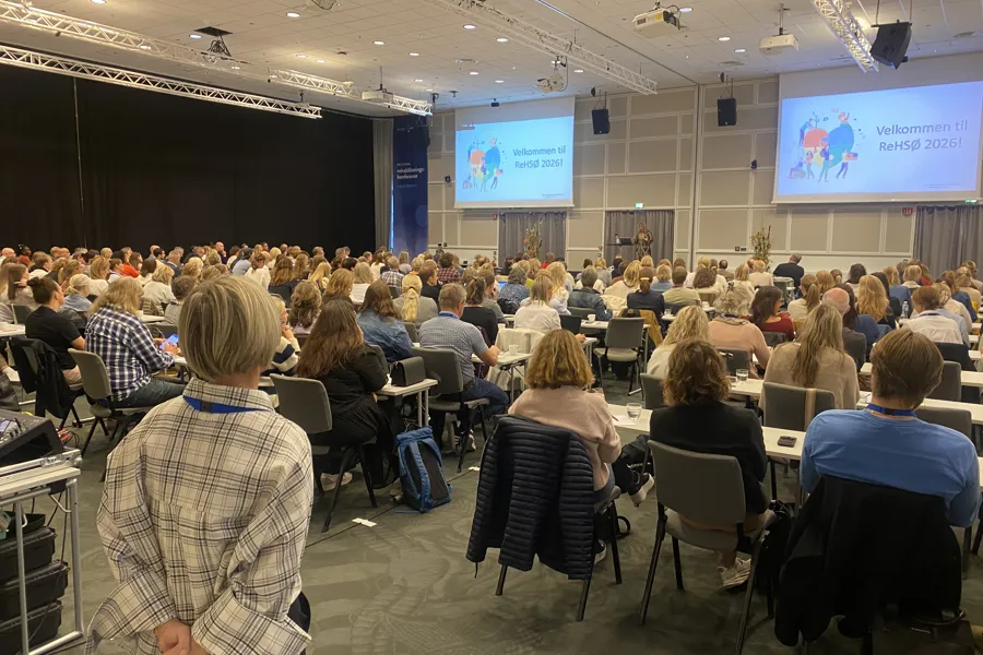 En gruppe mennesker som sitter i et rom og ser på en skjerm