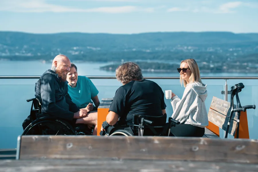 Flere samlet som drikker kaffe på takterrassen på Sunnaas sykehus. Noen sitter i rullestol.