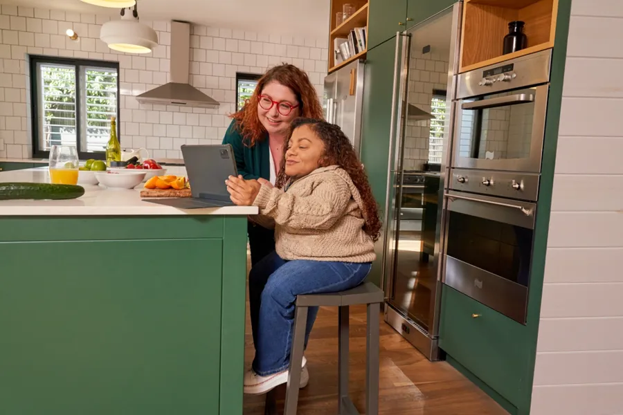 Dame med osteogenesis imperfecta som får hjelp av en venninne med nettbrettet