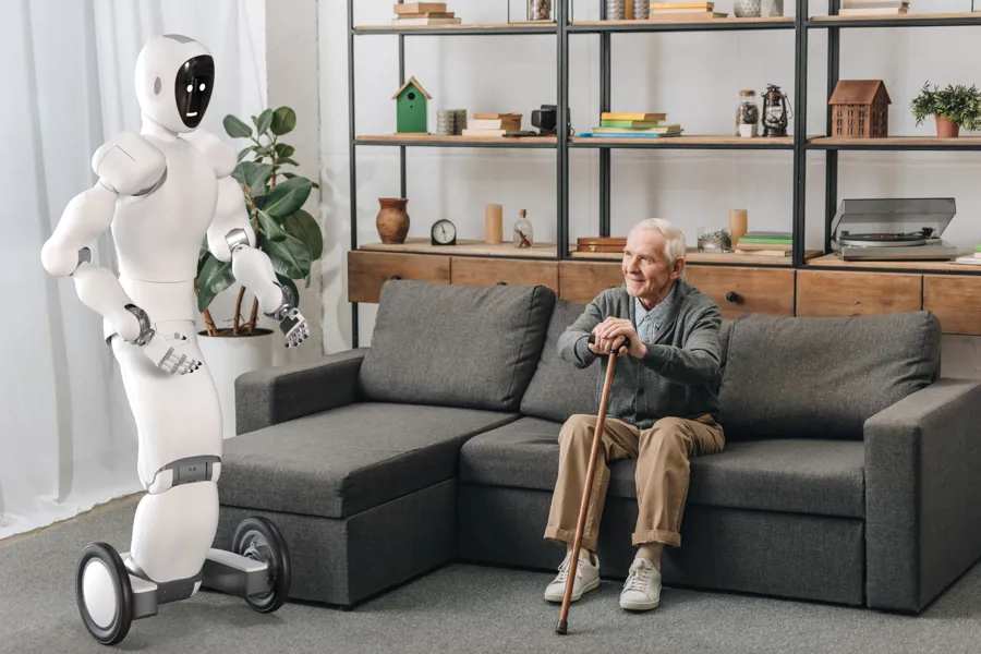 Gammel mann i sofa ser på hvit robot