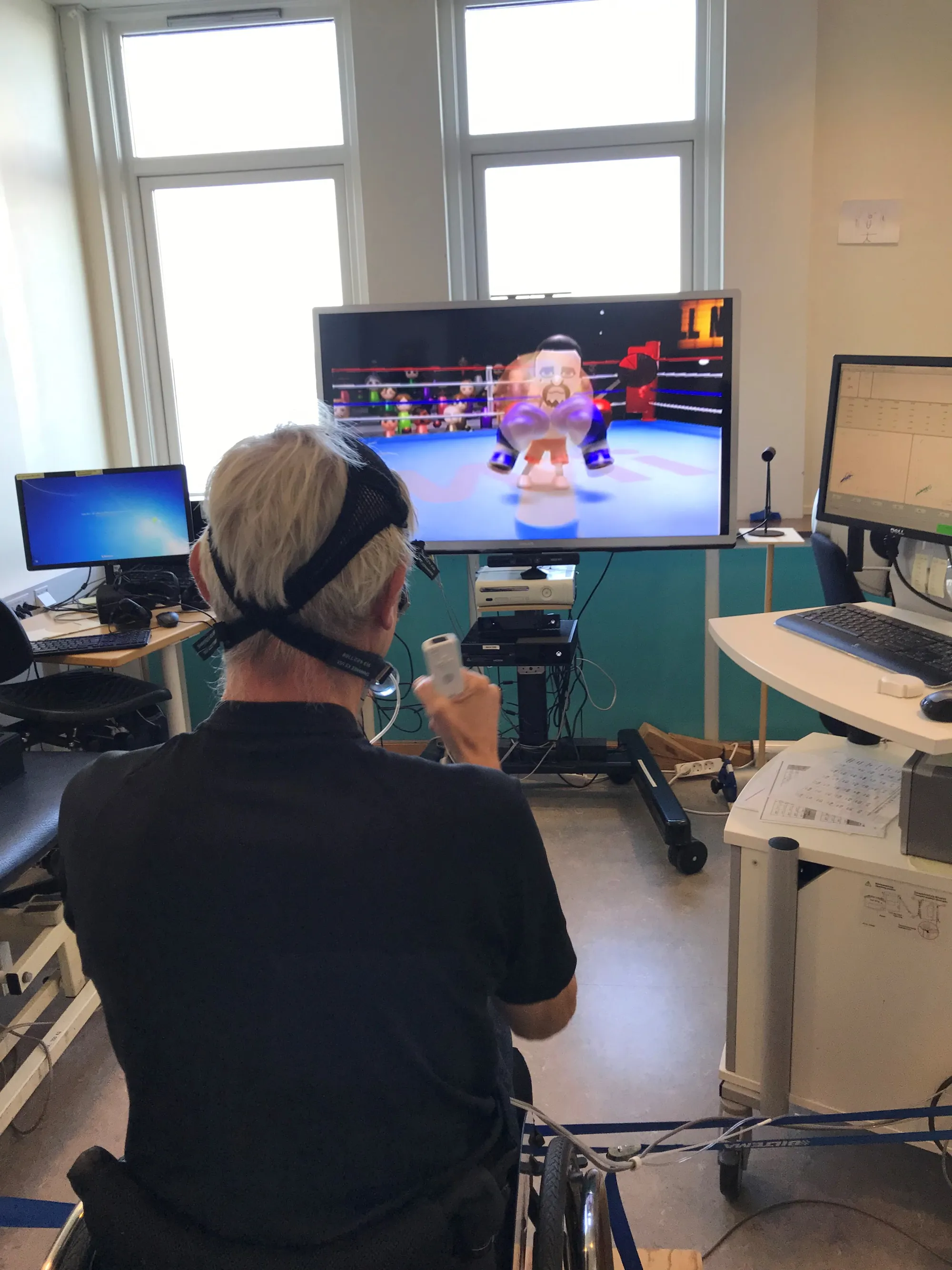 Person i rullestol spiller Nintendo Wii med tilkoblede måleinstrumenter på hodet