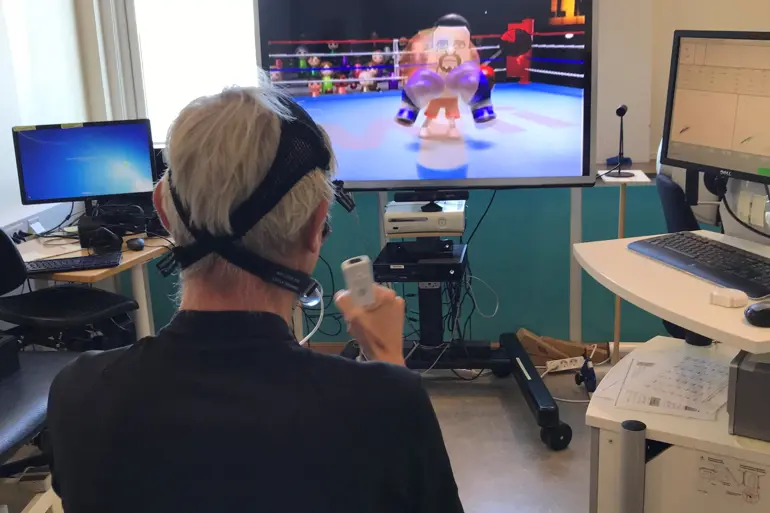 Person i rullestol spiller Nintendo Wii med tilkoblede måleinstrumenter på hodet