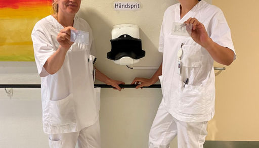 To damer står foran en dispenser og holder opp kort