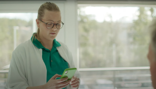 Jente holder mobiltelefon i hånden mens hun snakker med pasient