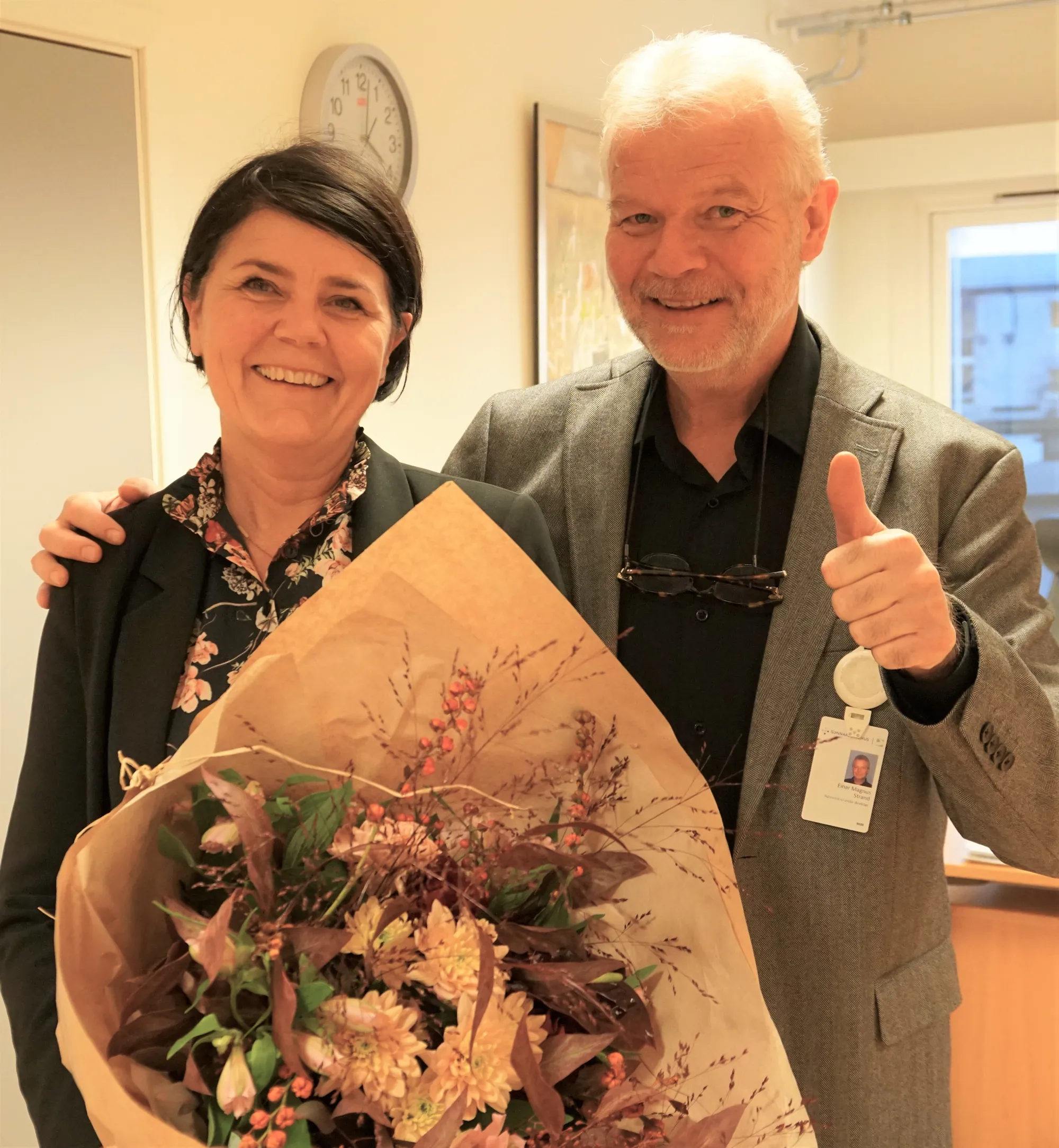 To smilende personer med blomsterbukett