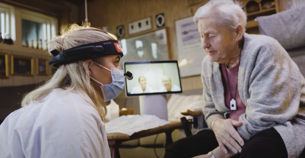 Eldre kvinne blir undersøkt av sykepleier med hodekamera