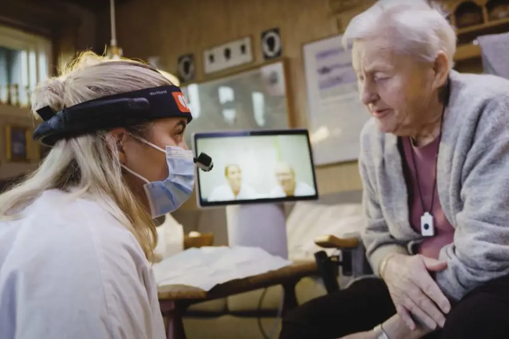 Eldre kvinne blir undersøkt av sykepleier med hodekamera
