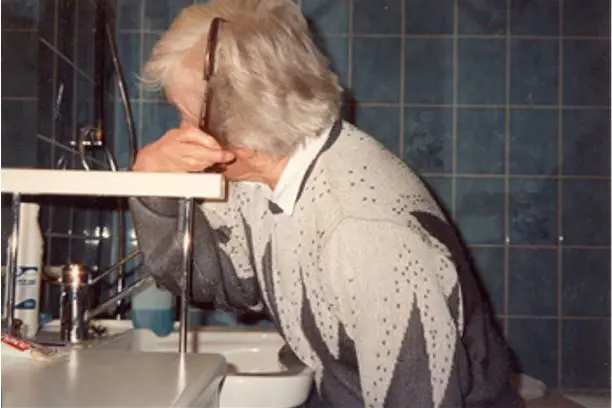 Bilde av dame som grer seg ved å støtte armen på høyt støttehåndtak ved vasken