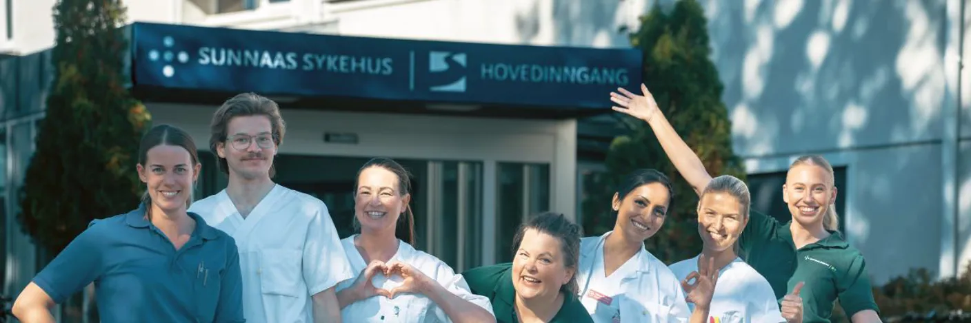 Bilde av helsepersonell som står foran inngangen til Sunnaas sykehus. De representerer tverrfaglig team.