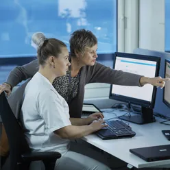 To kvinner som ser på en dataskjerm.