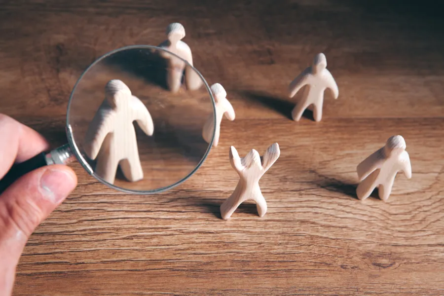 Illustrasjon av et menneske i søkelyset, sett gjennom forstørrelsesglass