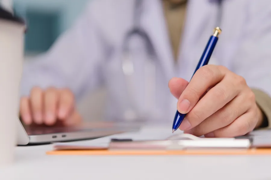 Lege som skriver på et papir