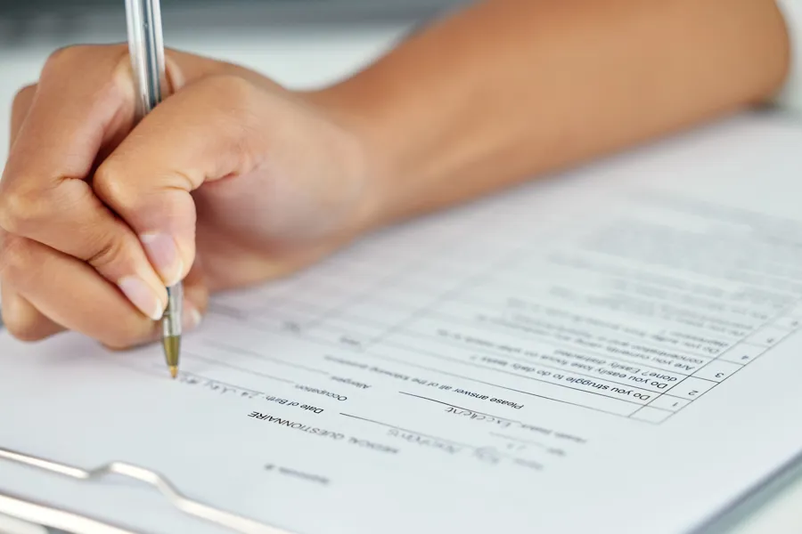 Person som fyller ut et skjema med penn og papir