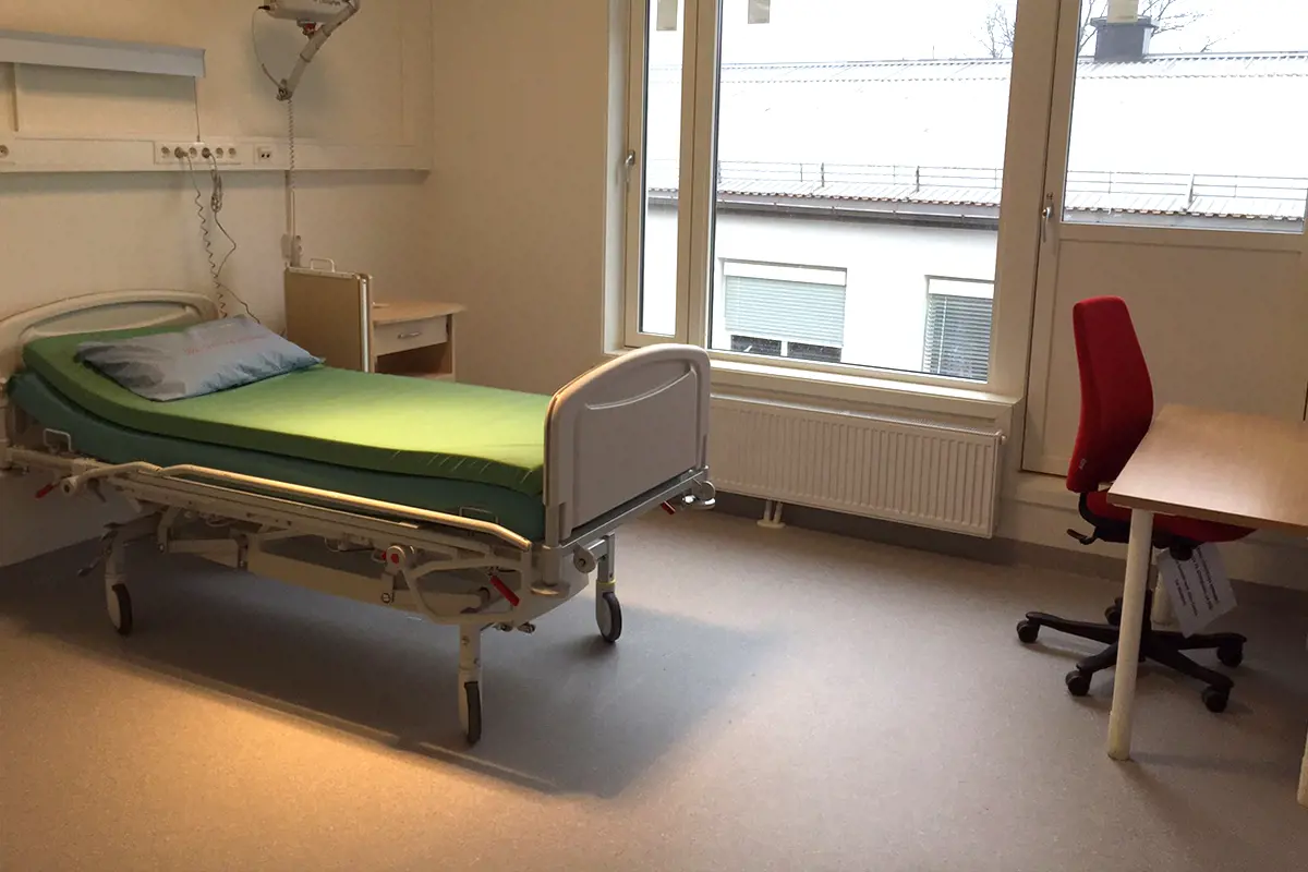 Et sykehusrom med en seng og en stol
