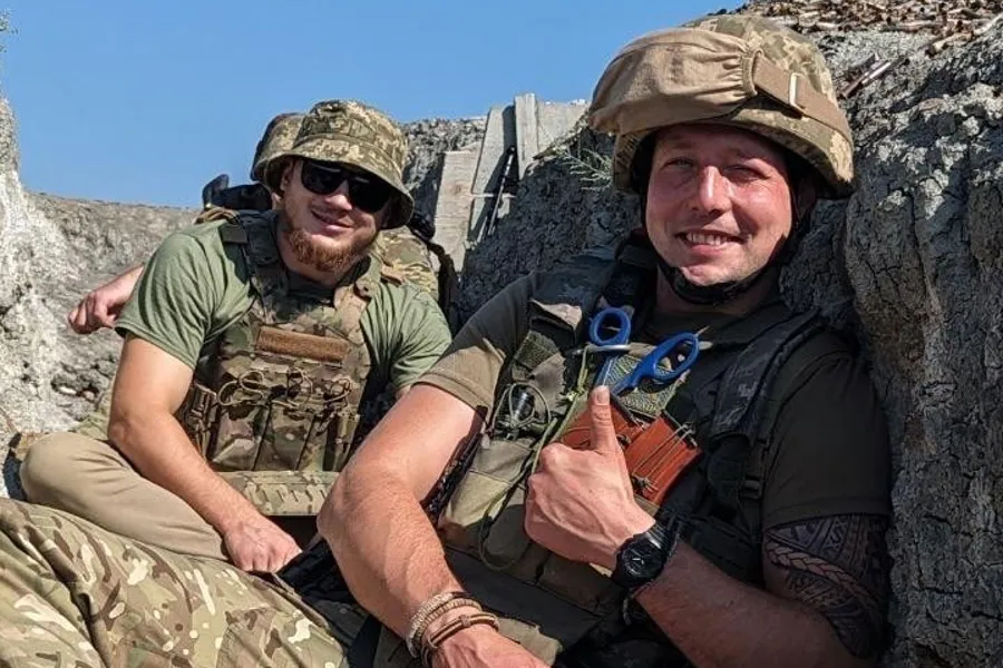 Serhii Pashkovskyi og en annen soldat sitter og ser mot kamera.