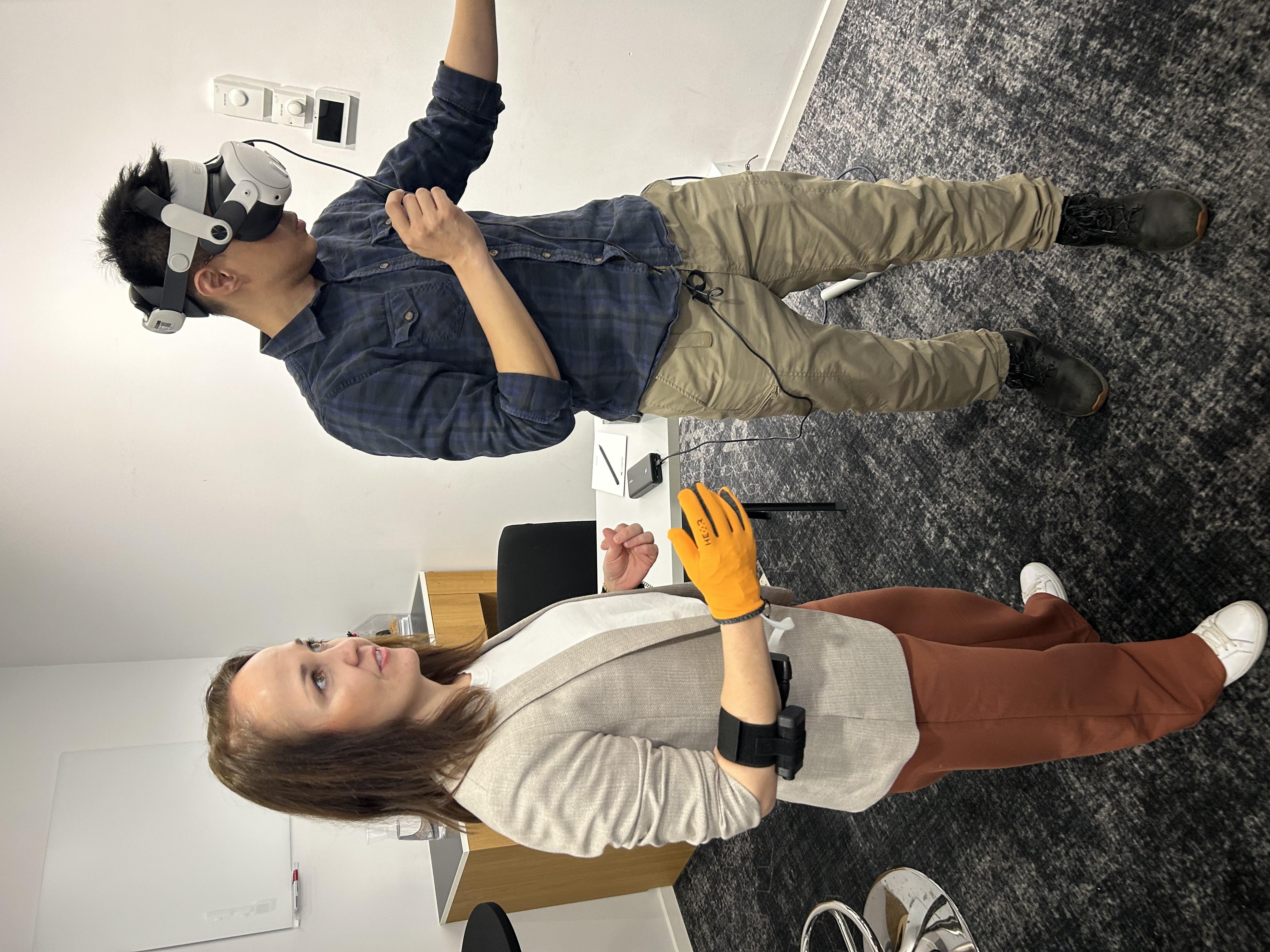 Anne-Marthe Sanders tester en hanske med digitale sensorer. Ved siden av henne står en forsker fra Singapore og tester VR-briller