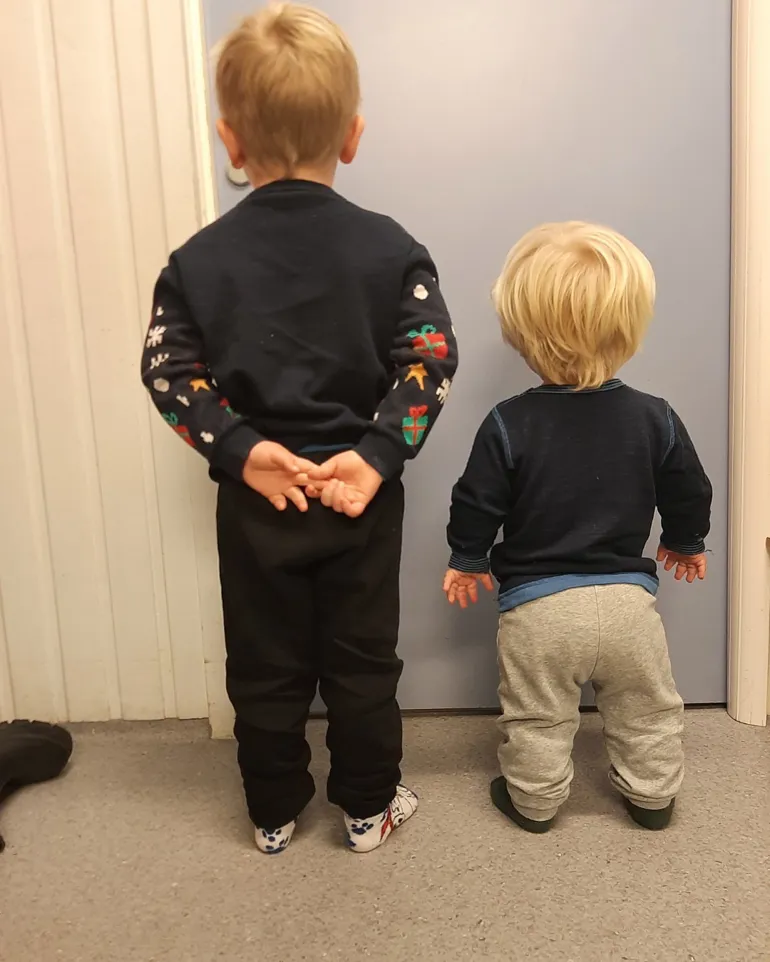 To barn som står foran en hvit dør
