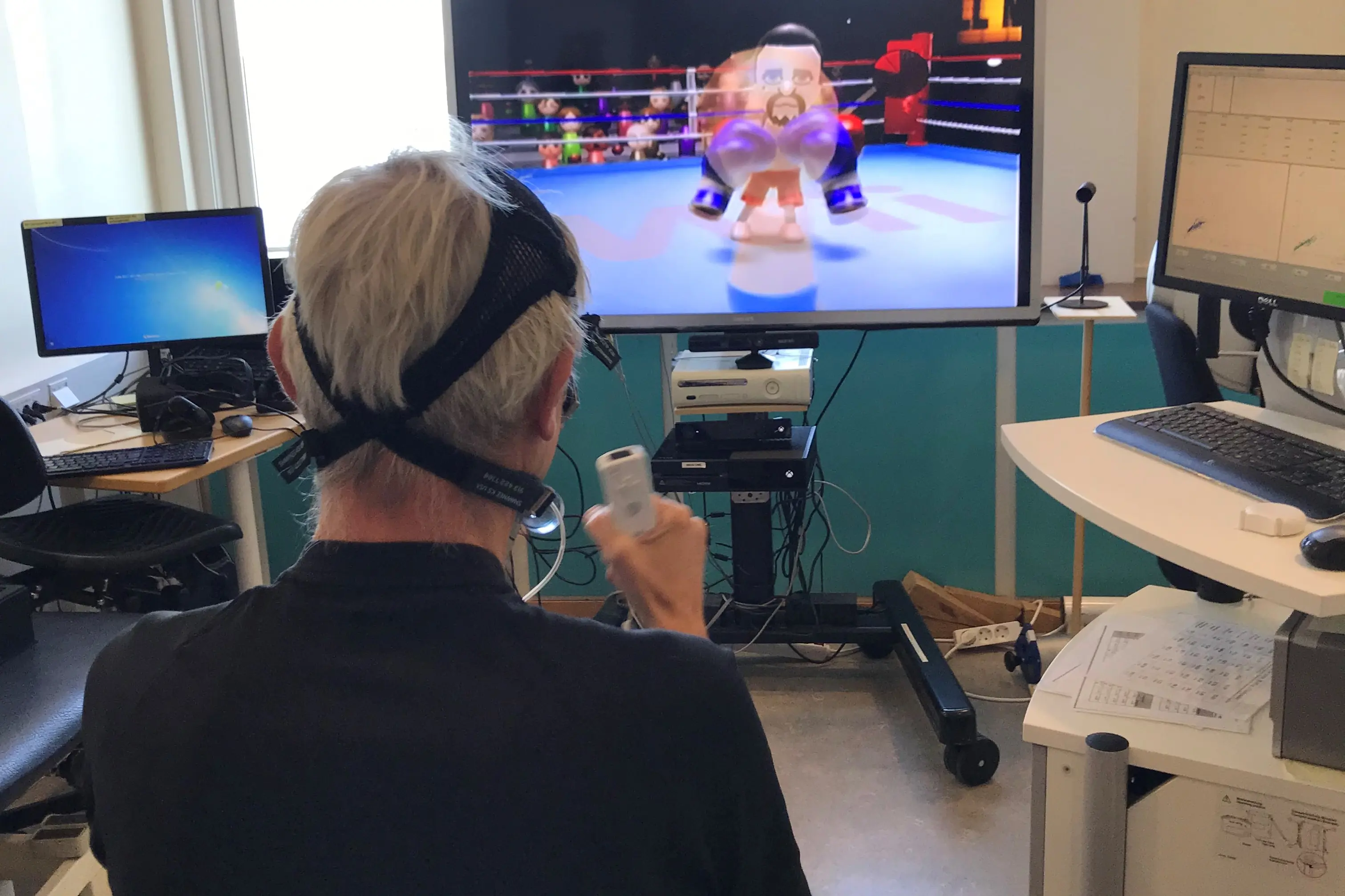 Person i rullestol spiller Nintendo Wii med tilkoblede måleinstrumenter på hodet
